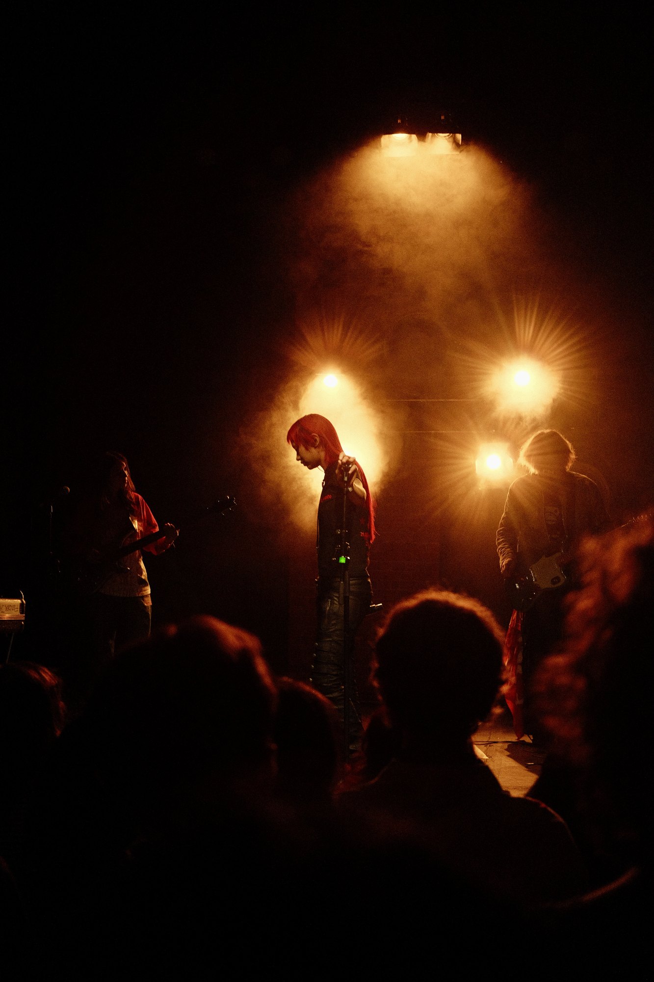 akriila on stage in warm orange light, head bowed