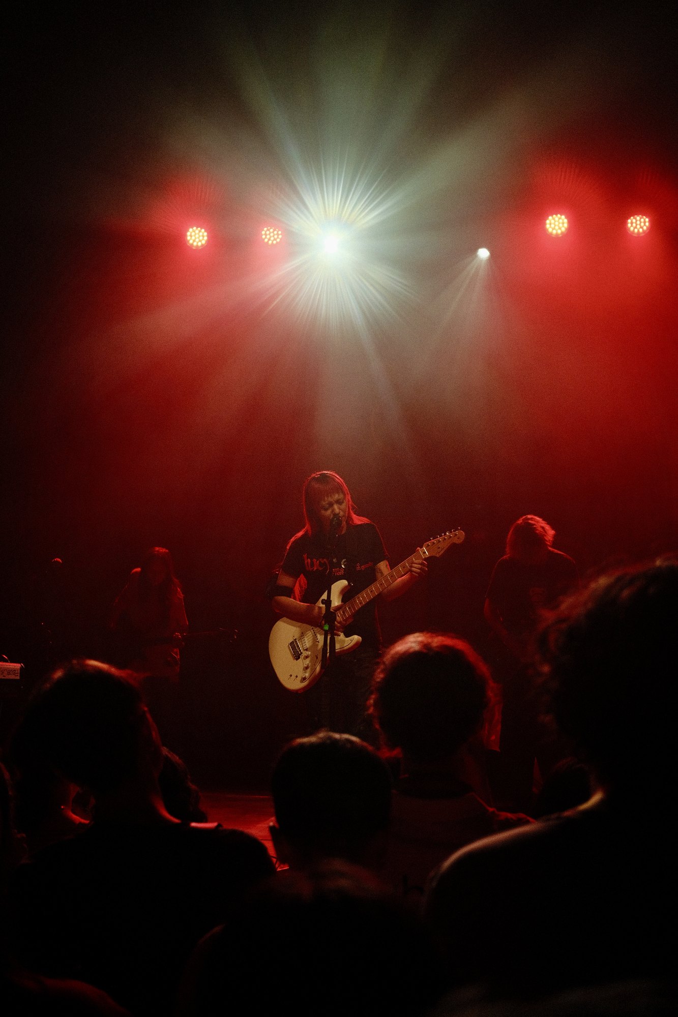 akriila playing guitar in red light with a starburst above